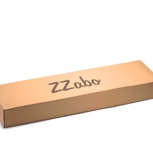 Puede incluir: Una caja de cart&oacute;n marr&oacute;n con la palabra "ZZabo" impresa en la parte superior.
