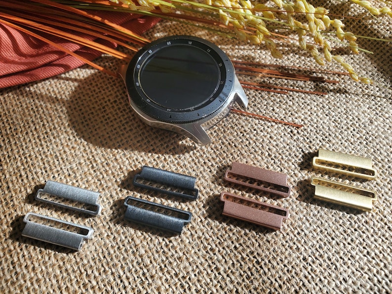 Pu&ograve; includere: Cinque diversi connettori per cinturino da orologio, due argentati, due neri e due dorati. I connettori sono in metallo e hanno una forma rettangolare con due fori al centro.