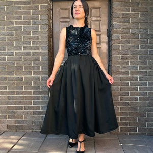 May include: A black sleeveless dress with a patterned bodice and a full skirt. The dress is worn with black heels.