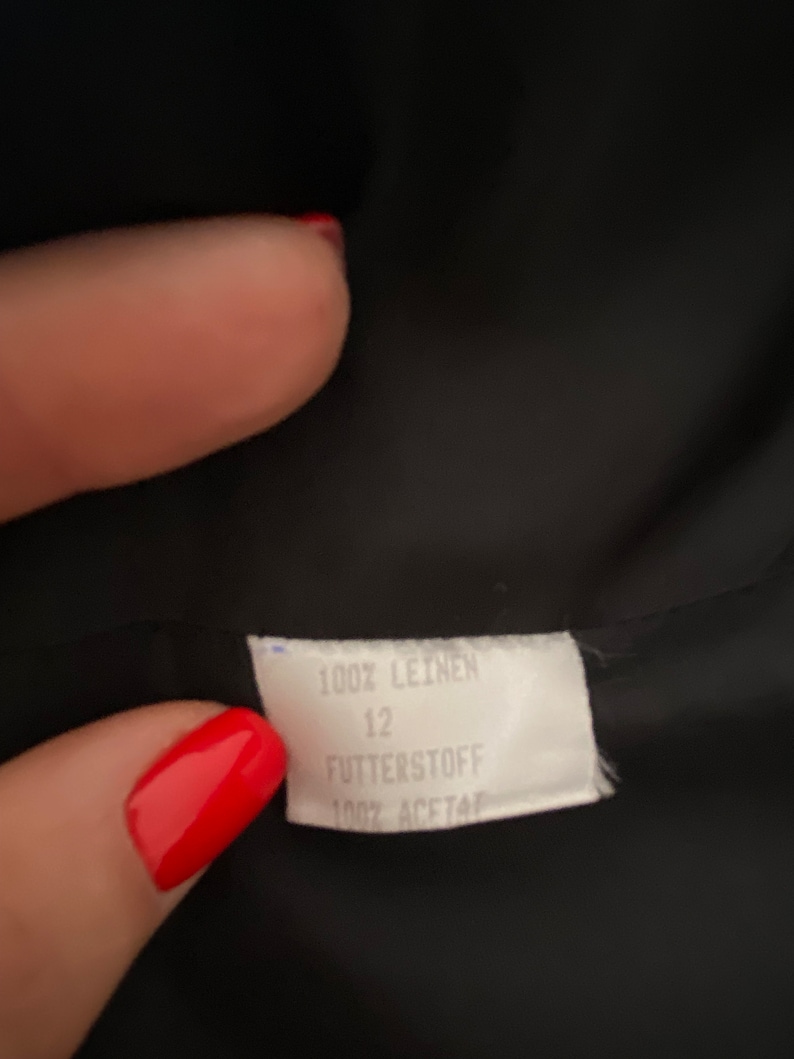 Puede incluir: Etiqueta blanca con texto negro que dice "100% Leinen 12 Futterstoff 100% Acetat"