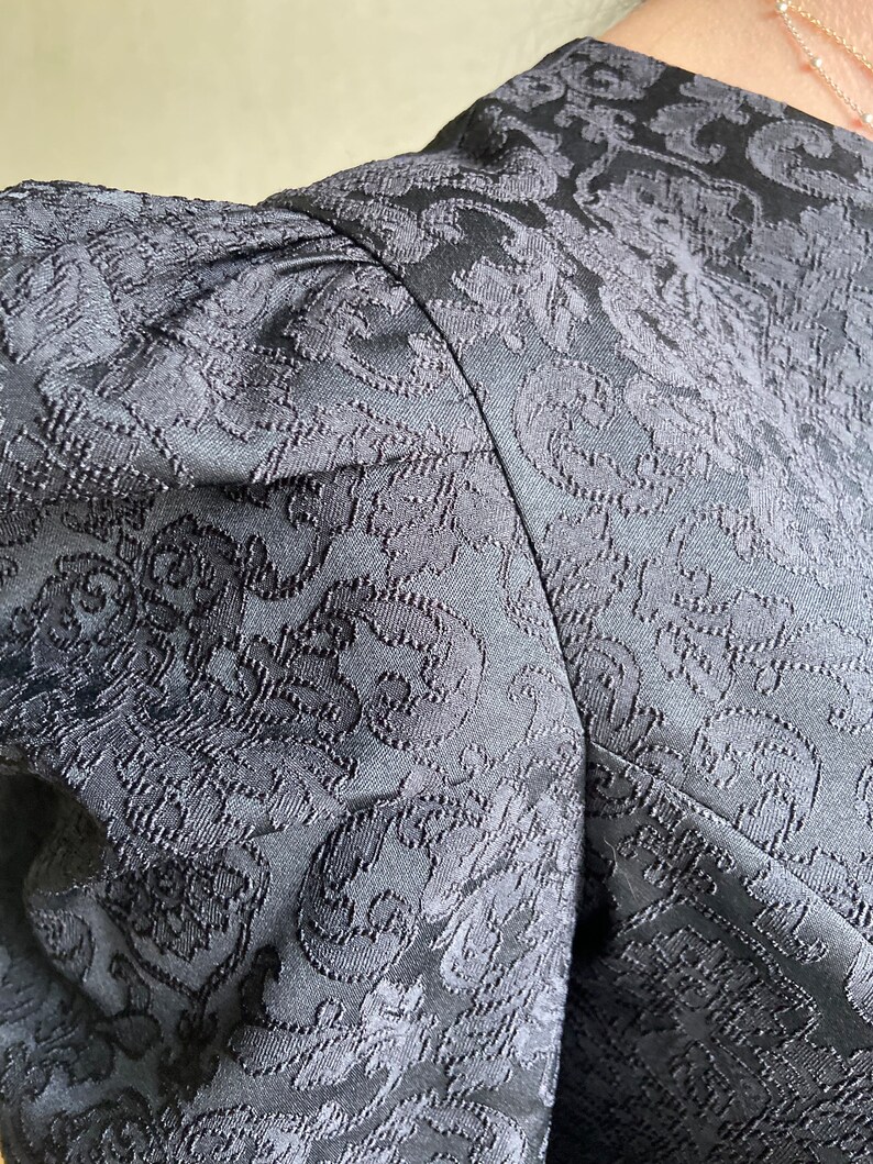 May include: Black dress with a floral pattern and puffed sleeves.