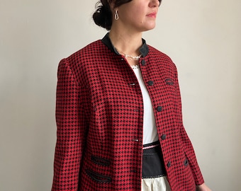 Puede incluir: Una chaqueta de color rojo y negro con estampado de pata de gallo, cuello negro y botones negros. La chaqueta tiene una silueta ajustada y se lleva con una camisa blanca y un cinturón negro.