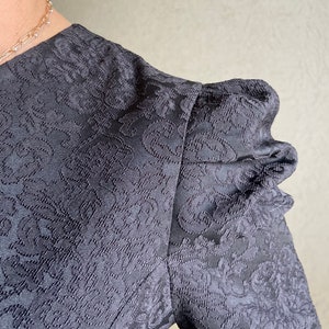 May include: Black dress with a floral pattern and puffed sleeves.