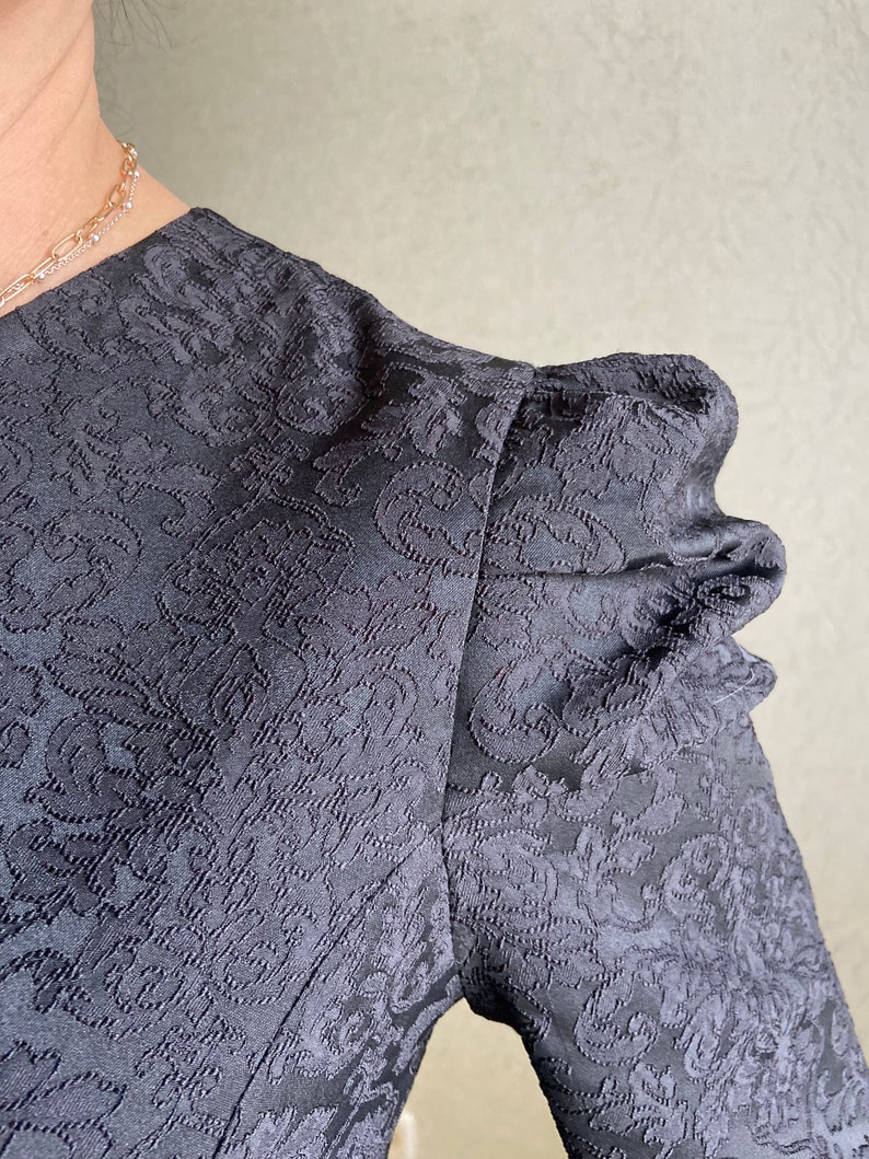 May include: Black dress with a floral pattern and puffed sleeves.