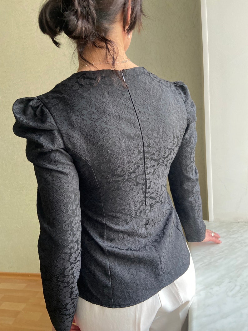 May include: Black long-sleeved blouse with a floral pattern and puffed sleeves.