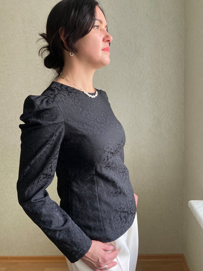 May include: A black long-sleeved blouse with a floral pattern and puffed sleeves.