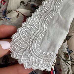 May include: White lace trim with a scalloped edge. The lace has a delicate floral pattern.