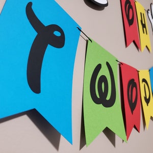 May include: A vibrant banner spelling "TWOODLES" in black on blue, green, red, and yellow pennants. The banner also features a Mickey Mouse cutout and the words "OH BOY".