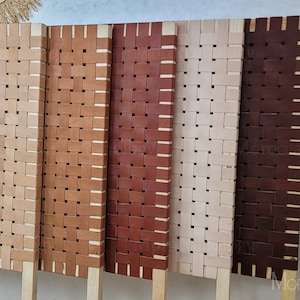 May include: Five headboard panels made of woven leather in various shades of brown, beige, and white. The panels are mounted on wooden posts and have a simple, modern design.