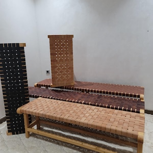 May include: A collection of handcrafted benches and a screen. The benches feature woven leather seats in shades of light brown, dark brown, and black. The screen is black with a woven design. The wooden frames are visible.