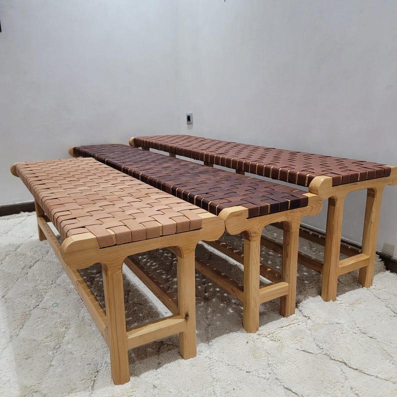 Peut inclure: Trois bancs en bois avec des assises en cuir tress&eacute;. Les bancs ont des cadres en bois brun clair et les assises sont en cuir tress&eacute; dans des tons de beige et de marron. Les bancs sont sur un tapis blanc.