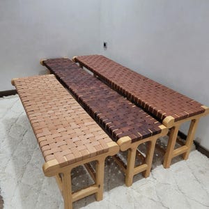 Peut inclure: Trois bancs en bois avec des assises en cuir tress&eacute; de diff&eacute;rentes nuances de marron. Les bancs ont des pieds et des cadres en bois clair. Les assises en cuir sont tress&eacute;es selon un motif en osier, cr&eacute;ant une surface textur&eacute;e.