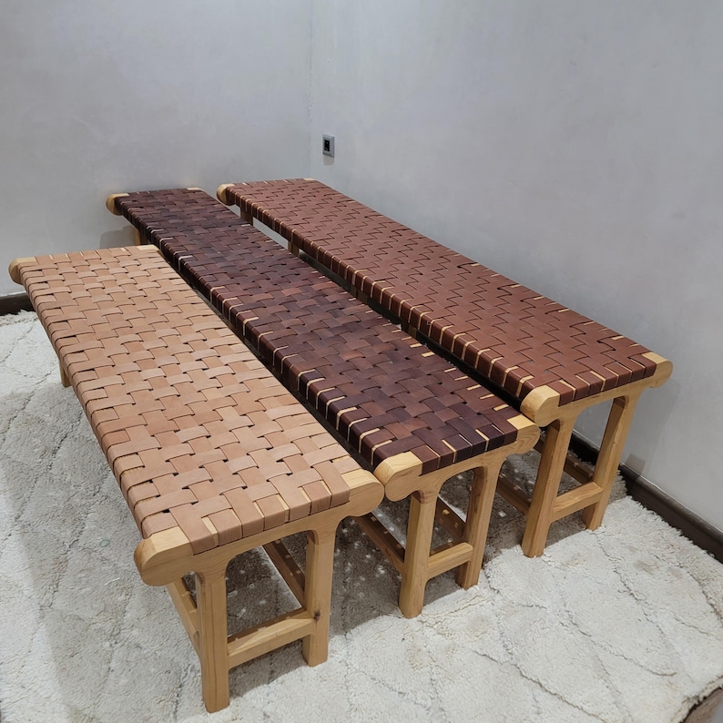 Peut inclure: Trois bancs en bois avec des assises en cuir tress&eacute; de diff&eacute;rentes nuances de marron. Les bancs ont des pieds et des cadres en bois de couleur claire. Le tissage en cuir cr&eacute;e une surface textur&eacute;e. Les bancs sont dispos&eacute;s en rang&eacute;e, pr&eacute;sentant les variations de couleurs.