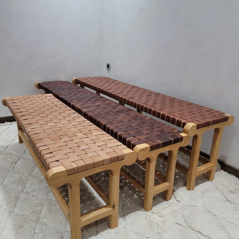 Peut inclure: Trois bancs en bois avec des assises en cuir tress&eacute; de diff&eacute;rentes nuances de marron. Les bancs ont des cadres en bois de couleur claire et sont dispos&eacute;s en rang&eacute;e. Les assises en cuir pr&eacute;sentent un motif tress&eacute;.