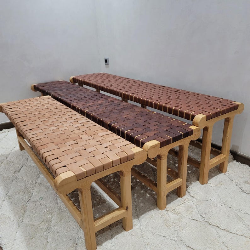 Peut inclure: Trois bancs en bois avec des assises tiss&eacute;es de diff&eacute;rentes nuances de marron. Les bancs ont des pieds et des cadres en bois de couleur claire. Les si&egrave;ges sont faits de lani&egrave;res de bois tiss&eacute;es, cr&eacute;ant une surface textur&eacute;e. Les bancs sont dispos&eacute;s en rang&eacute;e.