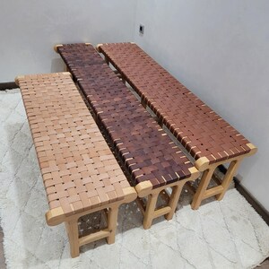 Peut inclure: Trois bancs en bois avec des assises en cuir tress&eacute; de diff&eacute;rentes nuances de marron. Les bancs ont des pieds et des cadres en bois clair. Le tissage du cuir cr&eacute;e une surface textur&eacute;e. Les bancs sont dispos&eacute;s en rang&eacute;e.