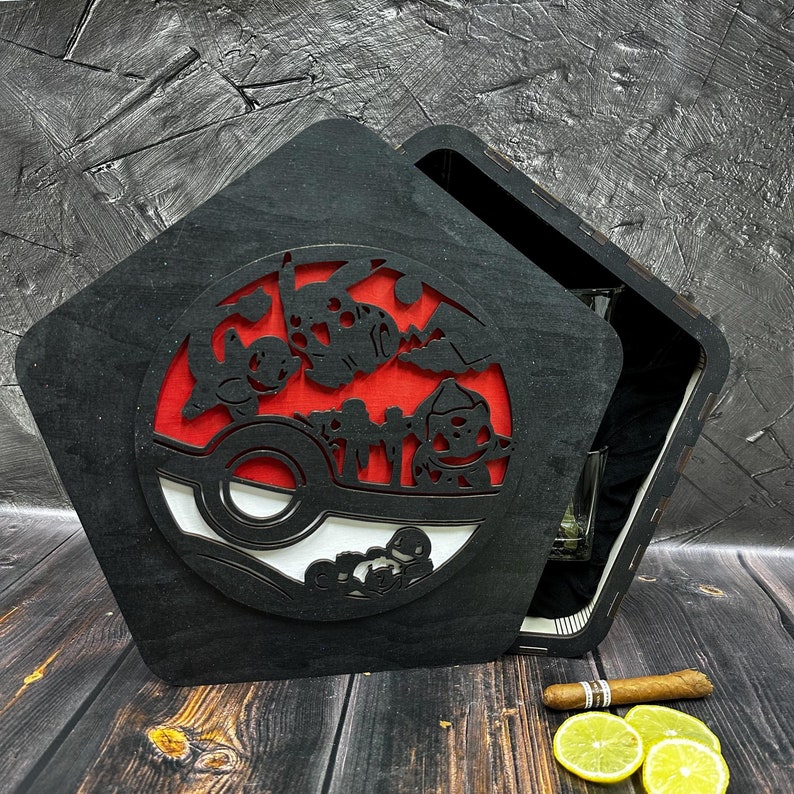 May include: A black wooden box with a hinged lid. The lid features a cutout design of a Pokeball with Pokemon characters. The box is open, revealing a clear glass inside.