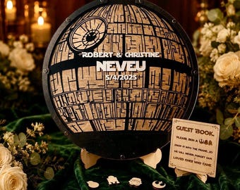 May include: A circular wooden guest book frame shaped like a space station with black and natural wood tones. It features the text ROBERT & CHRISTINE, NEVEU, and 5/4/2025. Includes a small sign reading GUEST BOOK and several small wooden tokens.