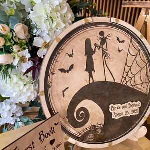May include: A round wooden plaque with a black and white silhouette of Jack Skellington and Sally from the Nightmare Before Christmas movie. The plaque has a black and white swirl design and the text "Patrick and Stephanie August 26, 2021".