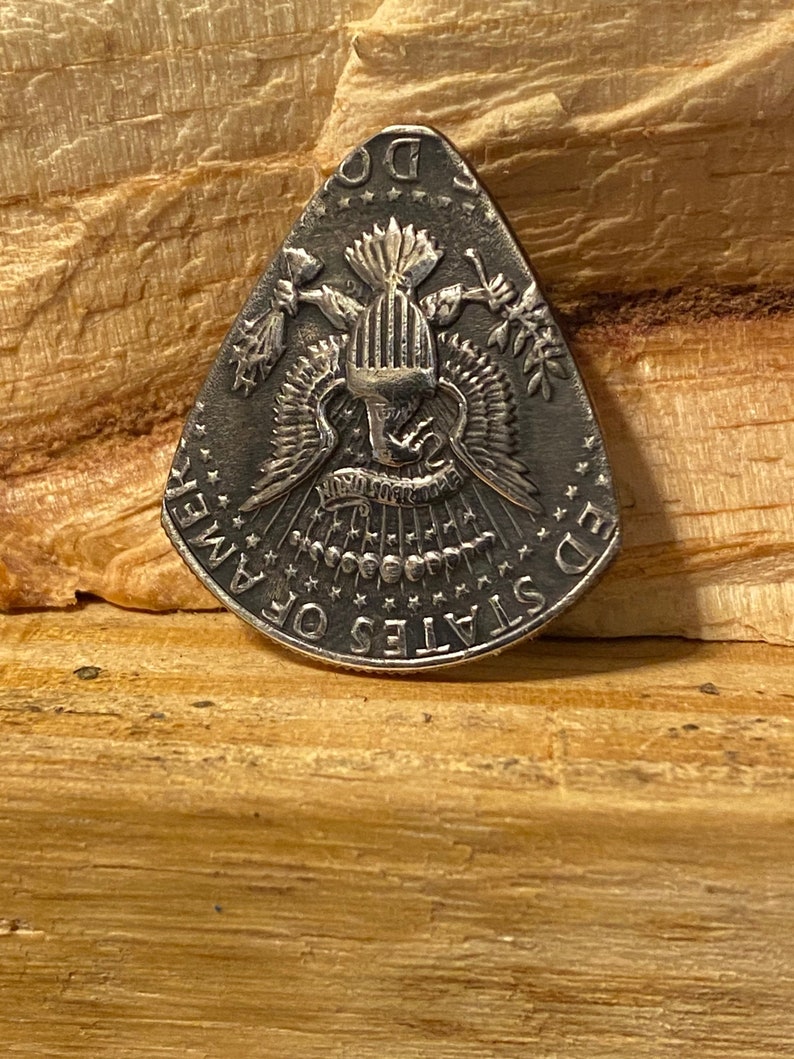 Pu&ograve; includere: Un plettro per chitarra in argento a forma di triangolo con le parole "United States of America" e "E Pluribus Unum" attorno al bordo. Il centro del plettro presenta un'immagine stilizzata di un'aquila con le ali spiegate.