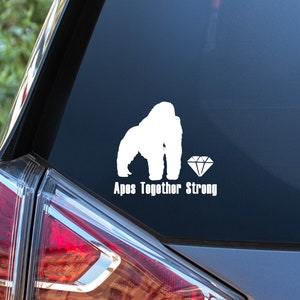 May include: A white vinyl sticker with a gorilla silhouette and a diamond, with the text "Apes Together Strong" on a gray car.