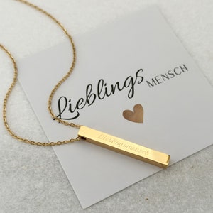 Puede incluir: Collar de barra de oro con una cadena delicada. La barra está grabada con el texto "Lieblingsmensch", que se traduce como "persona favorita" en español.