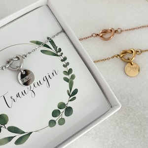 May include: Three delicate bracelets in silver, rose gold, and gold. Each features a heart-shaped knot design and a small, round charm. One bracelet is displayed inside a white box with the word "Trauzeugin" and a green leaf design.