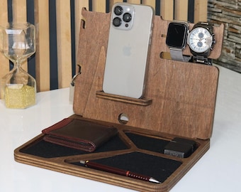 May include: A wooden desk organizer with compartments for a phone, watch, wallet, pen, and other small items. The organizer is made of light brown wood and has a dark brown leather wallet.