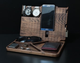 May include: A wooden organiser with compartments for a phone, watches, glasses, and other small items. The organiser has a dark brown finish and is made of wood.