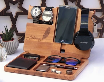 May include: Wooden organizer with compartments for a phone, watches, glasses, and other accessories. The organizer is personalized with the name "Johnny" and a feather design. It also includes a headphone holder with the word "Piranha" printed on it.
