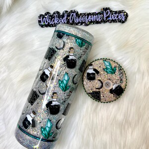 May include: A silver glitter tumbler with a green and black potion bottle design. The tumbler has a matching lid with the same design. The tumbler is labeled "Wicked Awesome Pieces".