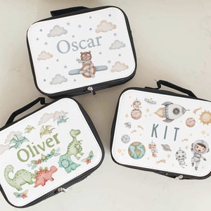 Puede incluir: Tres bolsas de almuerzo personalizadas con diferentes dise&ntilde;os. La primera bolsa tiene un dise&ntilde;o azul y blanco con nubes, estrellas y un oso piloto con el nombre "Oscar". La segunda bolsa tiene un dise&ntilde;o verde y blanco con dinosaurios y el nombre "Oliver". La tercera bolsa tiene un dise&ntilde;o blanco con planetas, estrellas, un cohete y un astronauta con el nombre "Kit".
