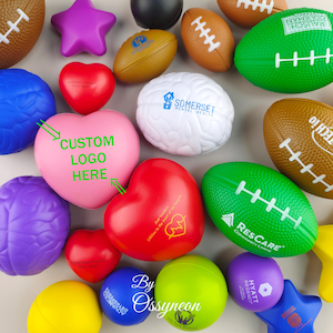 May include: Assortment of colorful stress balls in various shapes, including hearts, footballs, and a brain. Some stress balls have custom logos and text, such as "CUSTOM LOGO HERE", "Somerset Mental Health", and "ResCare Community Living".