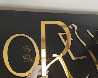 May include: Gold mirror letters spelling "ORE" with a star design. The letters are attached to a black background. The text "By Ossneon" is visible in the lower left corner.