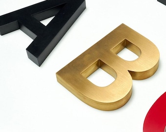 Könnte beinhalten: Drei dreidimensionale Buchstaben, A, B und C, aus verschiedenen Materialien. Der Buchstabe A ist schwarz, der Buchstabe B ist golden und der Buchstabe C ist rot.