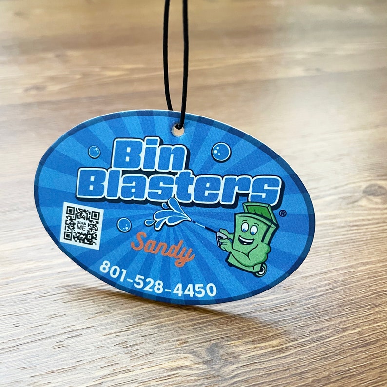 May include: A blue and white oval car air freshener with the text "Bin Blasters" and a cartoon trash can character. The text "Sandy" and a phone number are also included.