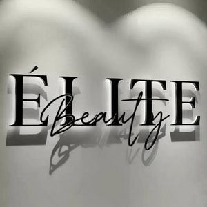 May include: Black illuminated sign on a white wall. The sign reads "&Eacute;LITE Beauty" in a combination of bold, capital letters and elegant cursive script. The letters cast shadows, creating a three-dimensional effect. The overall aesthetic is modern and sophisticated.