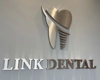 May include: A silver metal tooth with a screw implant, mounted on a white wall, with the text "LINK DENTAL" in silver letters below.