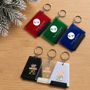 May include: Six rectangular ice scrapers with keychains. Three are translucent in red, green, and blue, featuring the white text ELITE ACCESS. Three are opaque in black, clear, and white, featuring the text LOCKED IN ON SUCCESS and a key icon.
