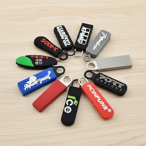 May include: A collection of colorful zipper pulls with various designs and text. The pulls are in shades of red, blue, black, green, and gray. Some have text like "X-KIDS", "Aquaplanet", "Ice", and "PCINFUNS".
