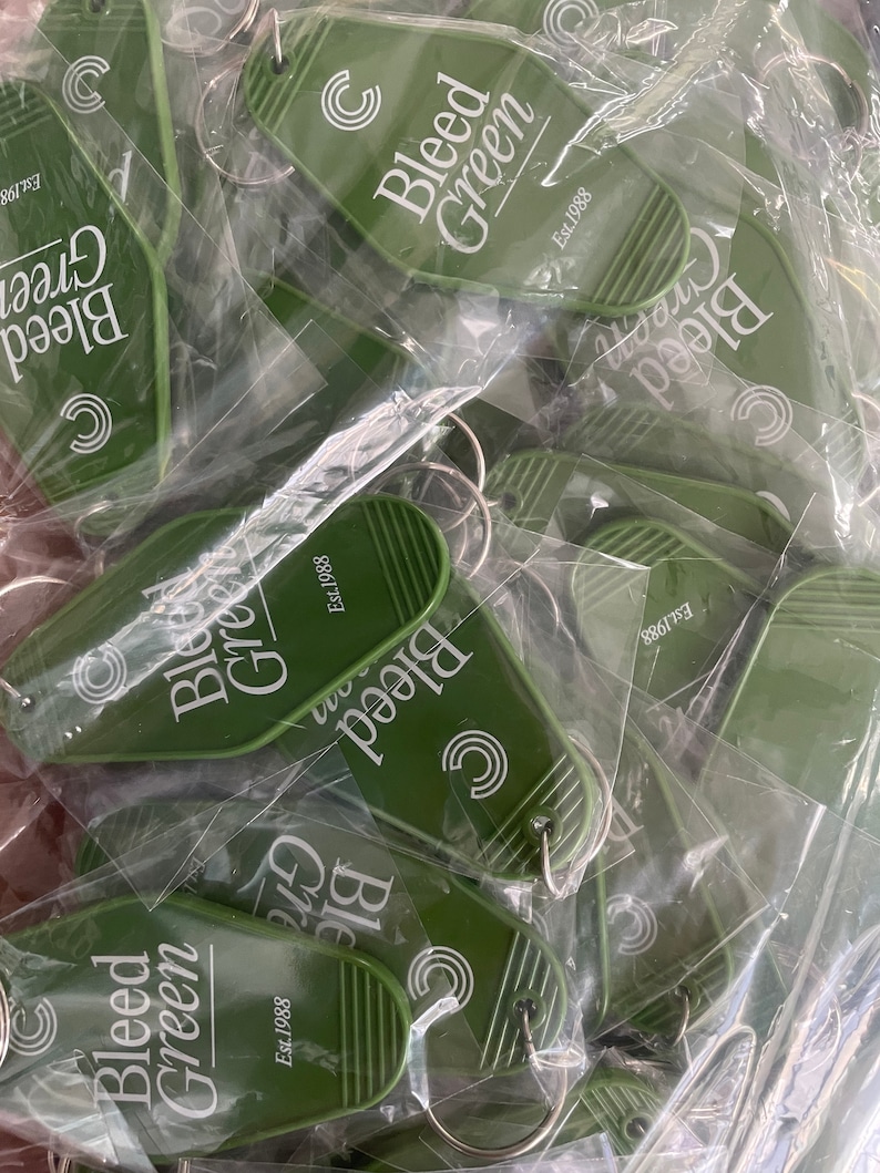 May include: A pile of green keychains with the text "Bleed Green" and "Est. 1988" on them. The keychains are in plastic packaging.