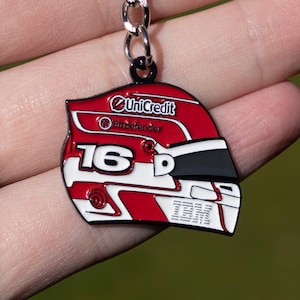 May include: A red, white, and black helmet-shaped keychain with the number 16 and the IBM logo. The keychain has a silver chain and the words "UniCredit" and "Bitdefender" are visible.
