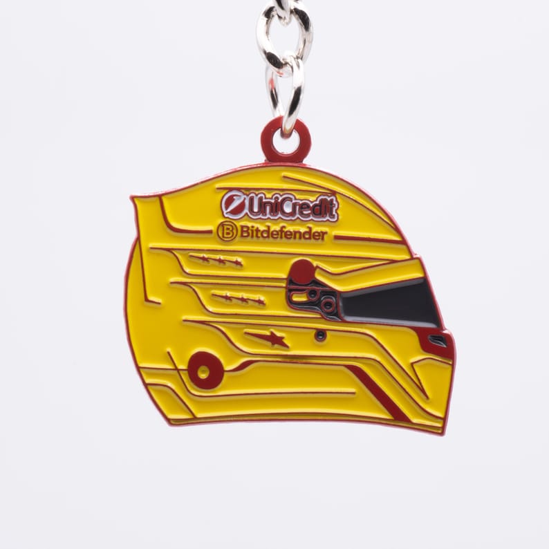 Pode incluir: Chaveiro de metal amarelo e vermelho em forma de capacete de corrida com os logotipos "UniCredit" e "Bitdefender" no lado.