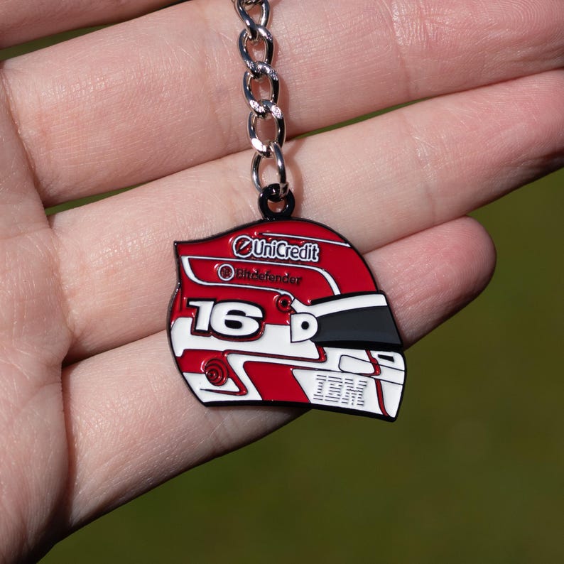 May include: A red, white, and black helmet-shaped keychain with the number 16 and the IBM logo. The keychain has a silver chain and the words "UniCredit" and "Bitdefender" are visible.