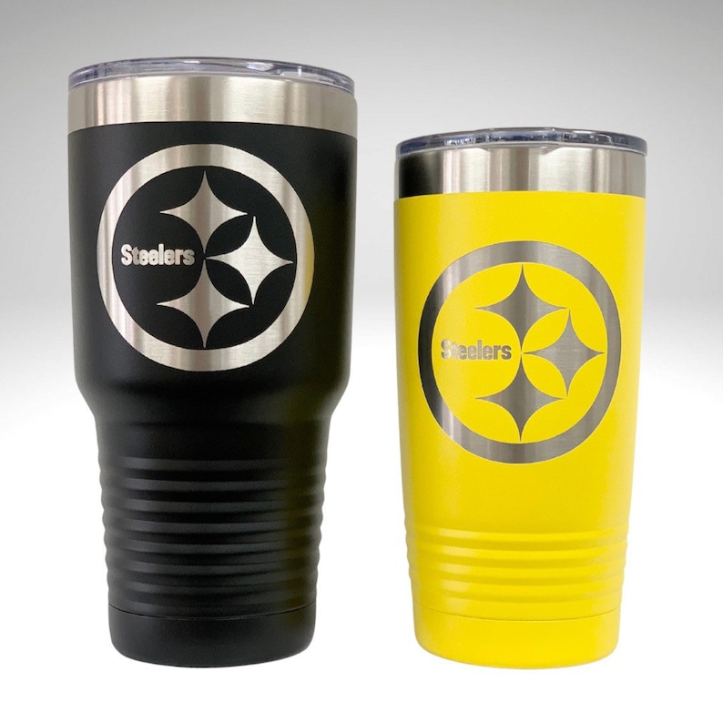 Puede incluir: Dos vasos de acero inoxidable con el logotipo de los Pittsburgh Steelers. El vaso m&aacute;s grande es negro y el m&aacute;s peque&ntilde;o es amarillo.