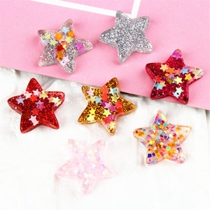 Peut inclure: Assortiment de six embellissements en résine en forme d'étoile scintillants dans différentes couleurs, notamment rouge, or, argent, rose et irisé.