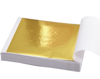 Può includere: Un pacco di fogli di oro, ogni foglio è sottile e delicato, con una finitura metallica scintillante. I fogli sono confezionati in una busta di carta bianca.
