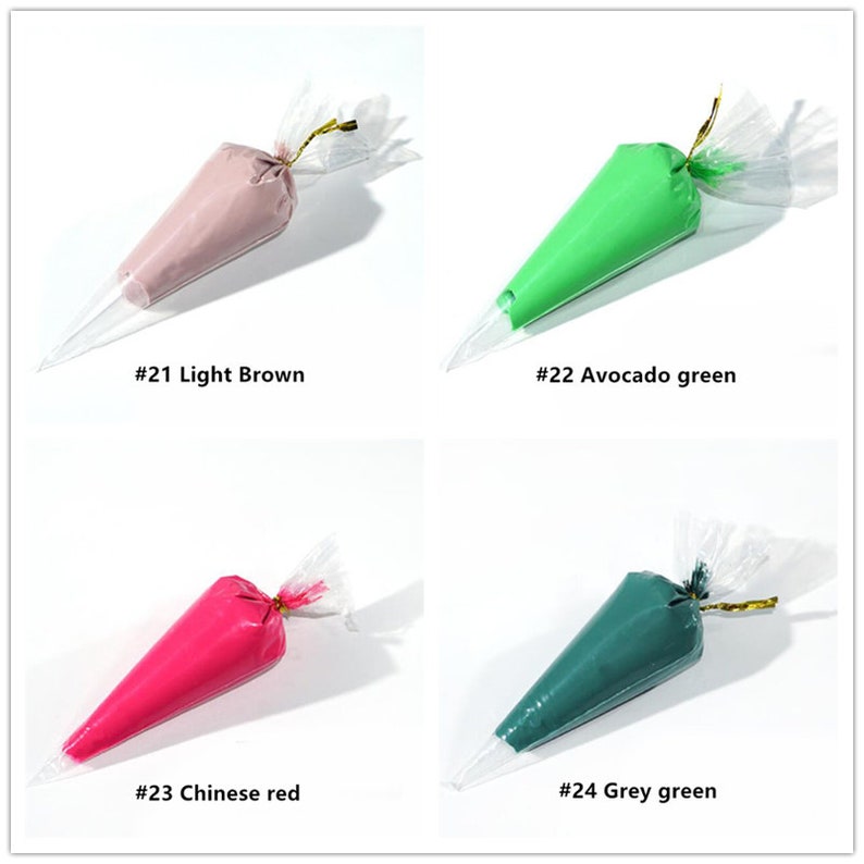 May include: Four plastic piping bags filled with different coloured frosting. The bags are labelled with numbers and colours: #21 Light Brown, #22 Avocado green, #23 Chinese red, and #24 Grey green.