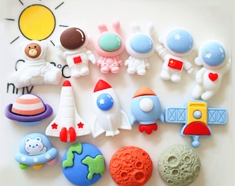 Może przedstawiać: Zestaw 14 kolorowych figurek z motywem kosmicznym, w tym astronauci, rakiety, planety i statek kosmiczny. Figurki są wykonane z miękkiego, giętkiego materiału i idealnie nadają się do kreatywnej zabawy.