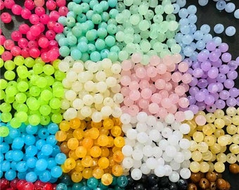 May include: Assortment of round, colorful beads in various shades of green, blue, pink, yellow, white, purple, brown, and red. The beads are made of plastic and are perfect for crafting.